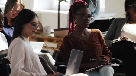 Group of happy professional multiethnic business women listening to seminar speech at modern light trendy office event.の写真素材