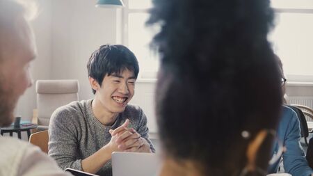 Multi ethnic team working on new business project. Happy Asian man sharing ideas at creative business agency meeting. 4Kの写真素材