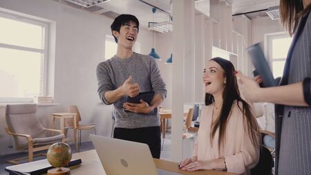 Mixed race colleagues talk to female boss. Happy millennial workers smile and meet CEO in light trendy office space 4K.の写真素材