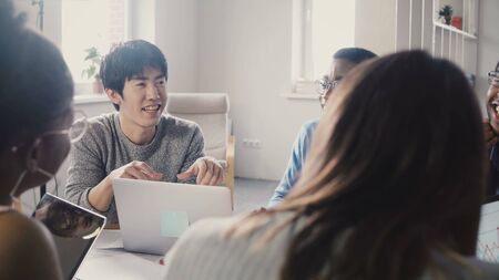 Multi ethnic team working on new business project. Happy Asian man sharing ideas at creative business agency meeting. 4Kの写真素材