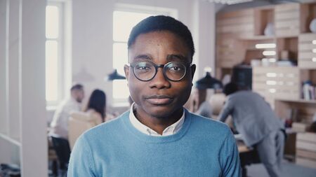 Handsome young African American businessman in glasses smiling at camera. Hipster stylish male office worker posing 4K.の写真素材