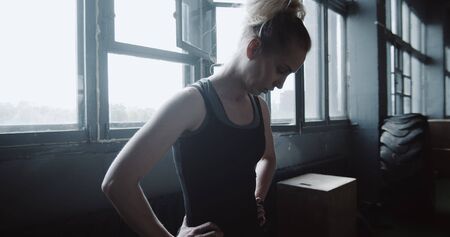 Young athletic blonde woman is exhausted and breathing heavy after extreme power exercising in large...