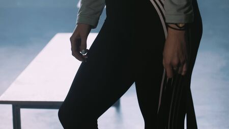 Close-up beautiful sporty woman in dark sportswear tights preparing to work out. Sports motivation...