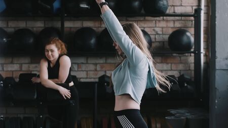 Young beautiful athletic Caucasian woman exercising with kettlebell weight, female fitness coach watching slow motion.の写真素材