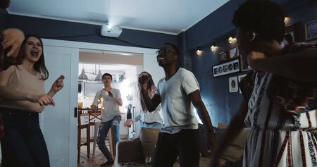 Cheerful multiethnic young college students having epic fun dancing together at party celebrating holidays slow motion.の写真素材