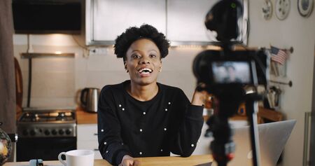 Happy young successful female black vlogger making new video for blog using professional camera at home slow motion.の写真素材