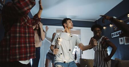 Happy young smiling Caucasian man dancing with friends at multiethnic party having epic fun on holidays slow motion.の写真素材
