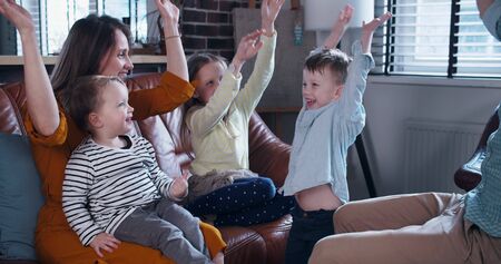 Happy young Caucasian mother and father join hands with three children, family togetherness time at home slow motion.の写真素材
