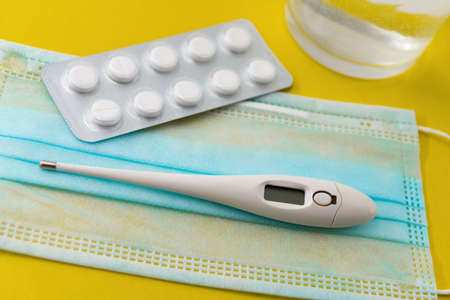 The photo shows a thermometer, a protective mask, and pills that symbolize protection and treatment...