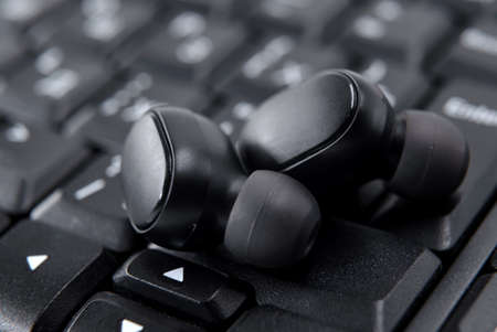 Modern youth wireless headphones close-up lie on the keyboard in black