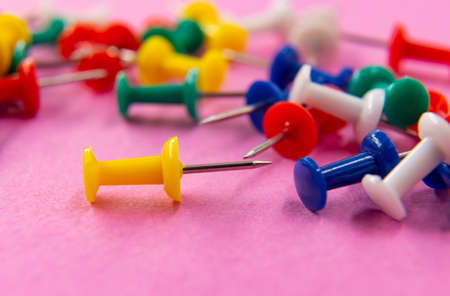 Multi-colored office buttons are scattered randomly on the pink surfaceの写真素材