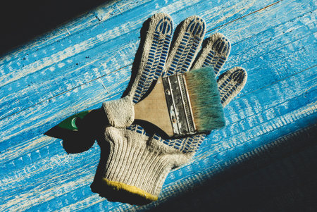 A construction glove with a paint brush lies on a wooden background. Items for painting works. Work glovesの写真素材
