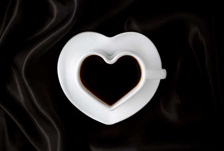 Coffee. Coffee cup on dark fabric or black background. Heart-shaped coffee cupの写真素材