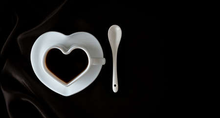 Coffee. Coffee cup on dark fabric or black background. Heart-shaped coffee cupの写真素材
