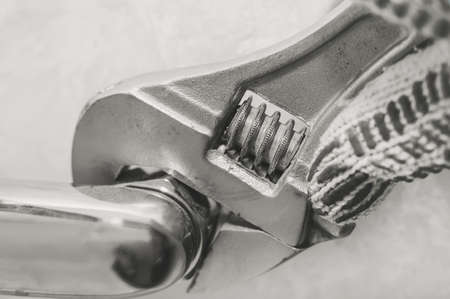 A wrench. Repair of a water tap. The hand clamps the nut with a wrench. Plumbing workの写真素材