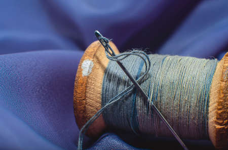Vintage spool with thread and a purple, blue needle. Tool for seamstresses and dressmakers