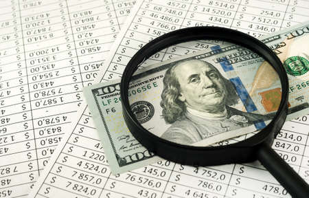 One hundred dollars through a magnifying glass close-up. Finance and business. Financial calculatorの写真素材