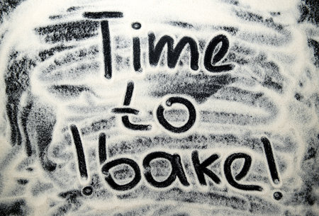 Time to bake lettering on a dark, black flour background. Background with inscriptionの写真素材