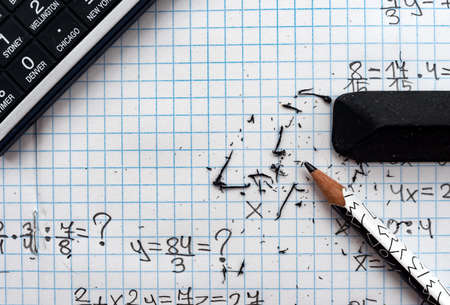Eraser, calculator and pencil. Plaid background of formulas with empty space for inscriptionsの写真素材