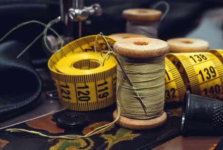 Vintage retro needle and thread, thimble and centimeter close-up. Tools for the work of a tailor, fashion designer or seamstress. Sewing productionの写真素材