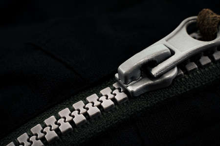 Lock with a gray zipper on black clothes close-up. jacket clasp