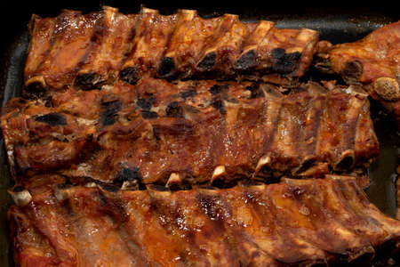 Fried ribs on a metal pan in fat. Meat products from beef