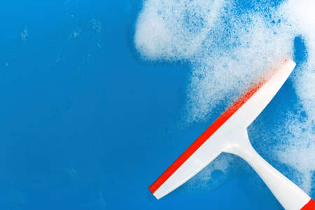 Wiper blade with soapy foam on a blue background. Free space for an inscription on a colored...