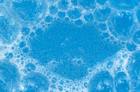 Soap foam in blue close-up. Foam bubbles on the surface of detergent or shampoo