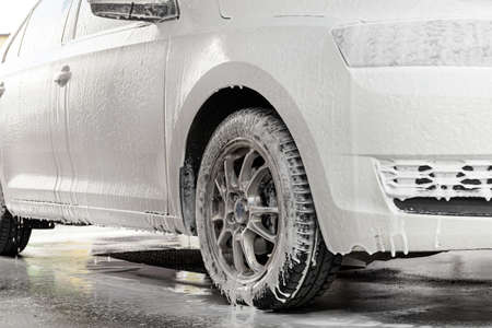The process of washing a white car at a self-service car wash