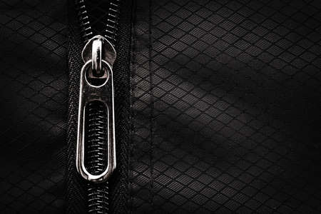 A lock with a silver zipper on a black background. Zipper