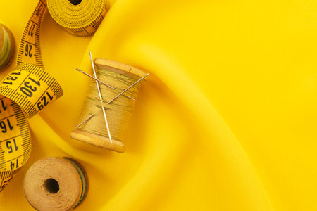Old retro sewing accessories lie on a yellow fabric. Needle and threadの写真素材