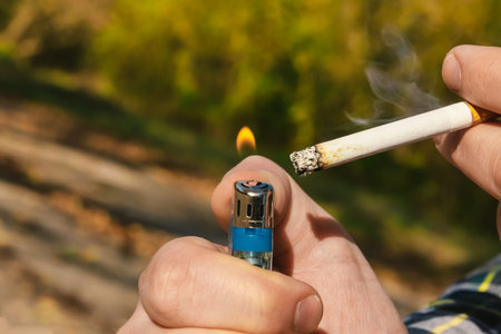 The hand lights a cigarette with a lighter. Smoking harms a person's health. Cigarettesの写真素材