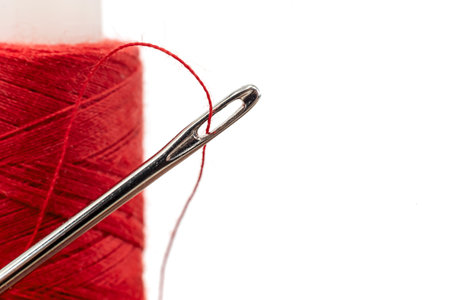 Needle with multi-colored threads on a white background. Eye of a needle close-up isolateの写真素材