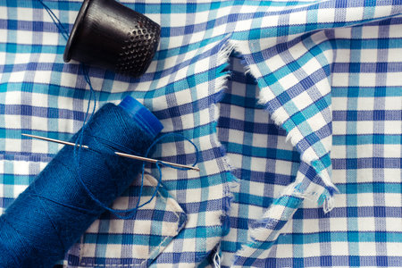 A needle and thread lies on torn or holey clothes. Shirt with a hole. Work for a seamstress or tailorの写真素材