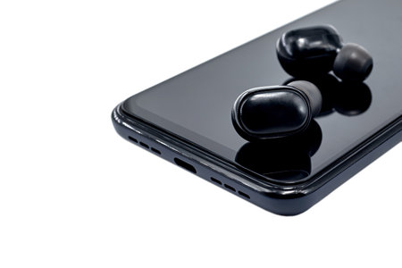Wireless headphones lie on the surface of a smartphone on a white background. wireless connection. technologiesの写真素材