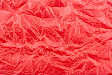 Texture of crumpled transparent polyethylene on a pink, red background, full frameの写真素材