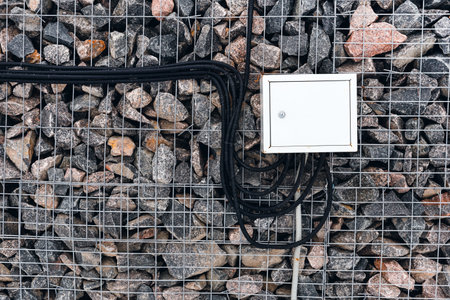 A transformer box with wires hangs on a stone fence. energy. power generationの写真素材