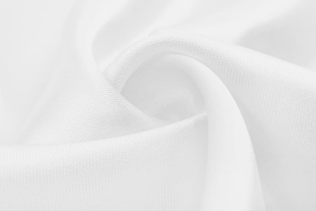A twisted piece of white fabric. White material or texture with waves and folds. Wrinkled white fabricの写真素材