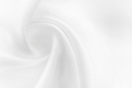 A twisted piece of white fabric. White material or texture with waves and folds. Wrinkled white fabricの写真素材