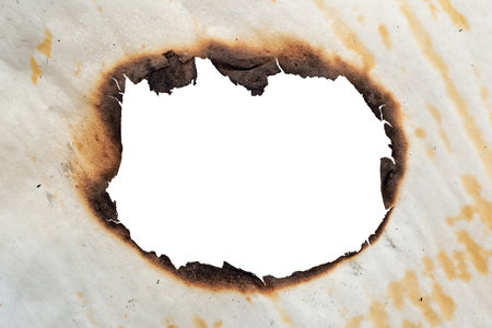 A hole in the scorched old yellow, crumpled paper. Baking paper after fire. Fireの写真素材