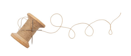 Old wooden spool of thread and needle on a white background. Sewing accessories