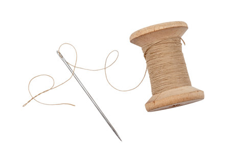 Old wooden spool of thread and needle on a white background. Sewing accessoriesの写真素材