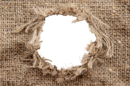 Hole in burlap. Torn piece of burlap fabric with a hole in the middle textureの写真素材