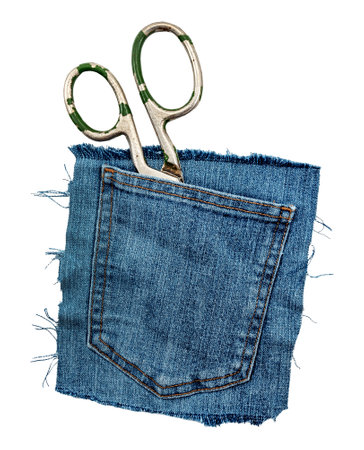 Tailor or seamstress scissors in a jeans pocket on a white background. A piece of torn denim. Pocket