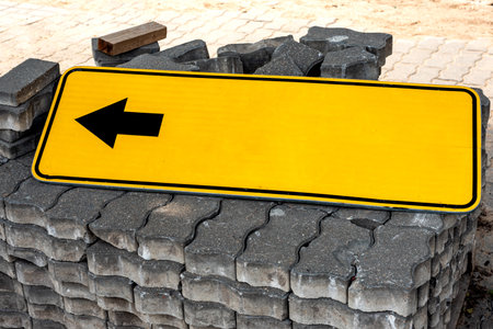 An empty yellow sign indicating the direction of travel lies on the paving stones. Signの写真素材