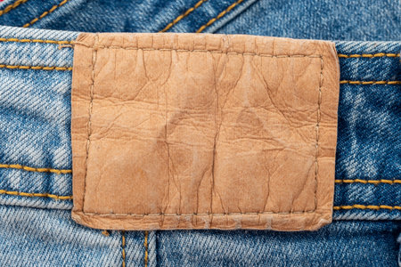 Empty worn leather patch on blue jeans. Empty space for writing. Blank leather jeans label