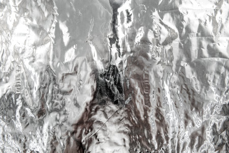 Texture of crumpled silver foil. Foil with dents, folds and wrinkles