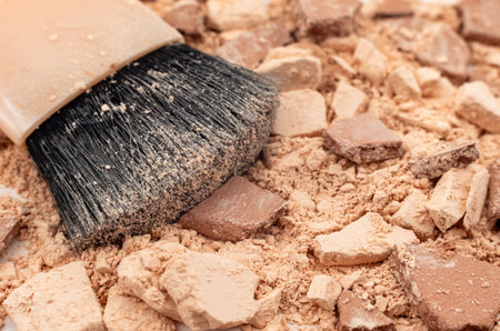Facial cosmetics. A powder brush lies on a surface with scattered powder