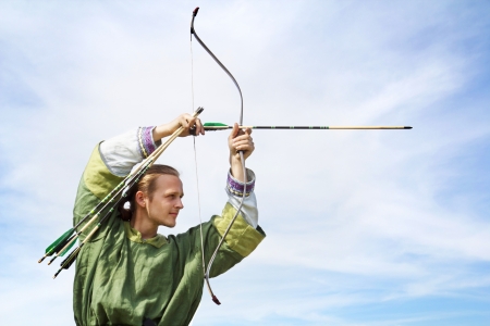 Young archer with bow and arrows in medieval costume aimingの写真素材