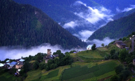 Mountain village with ancient towers on blue cloudy sky background 